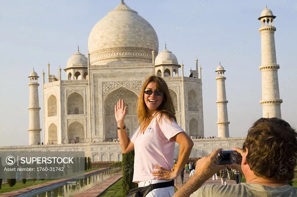 India, Agra, tourist man taking a photo of tourist woman in front of the Taj Mahal