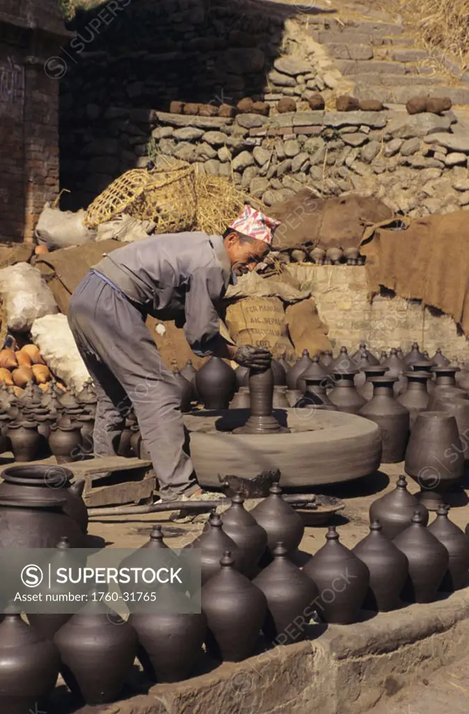 Nepal, Bhaktapur, Potter´s Square, local man shaping clay pots, finished pots out on display..