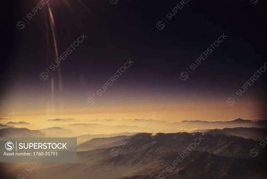 Nepal, Kathmandu Valley, overhead view of hill tops silhouetted among yellow haze and sky.