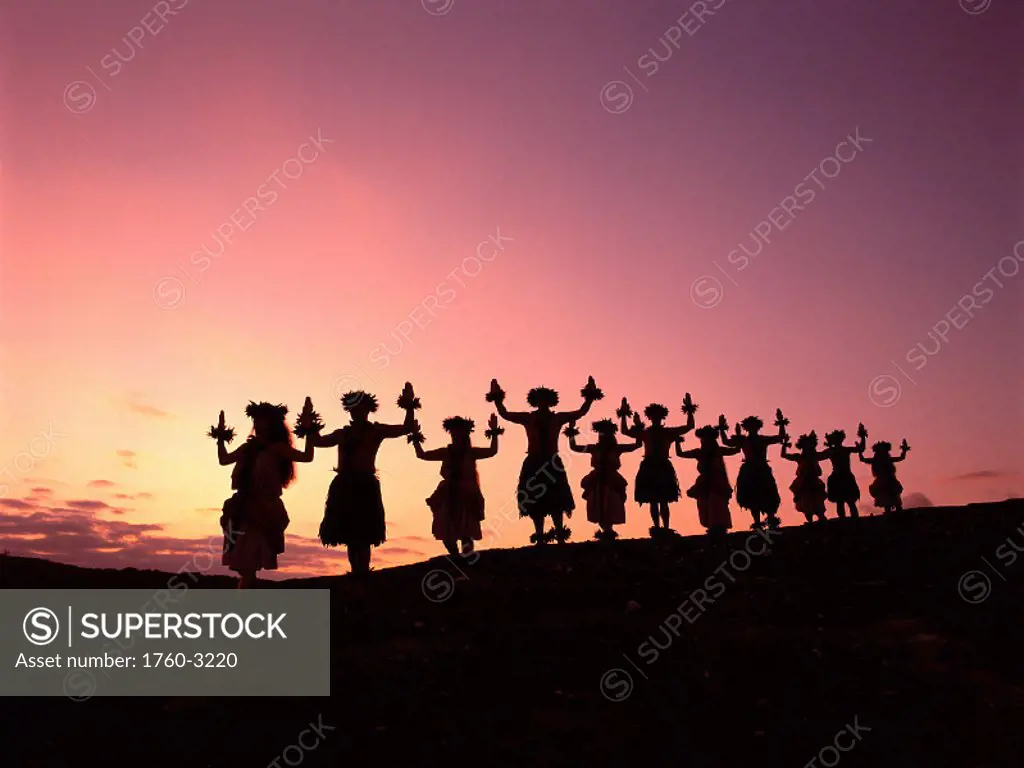 Hawaii, Hula halau posing w/ arms up, standing in row, silhouetted at sunset A36A