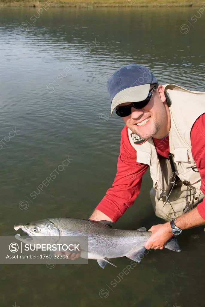 Usa, Alaska, Coghill Lake, A Fisherman Holding A Silver (Or Coho) Salmon (Oncorhynchus Kisutch).