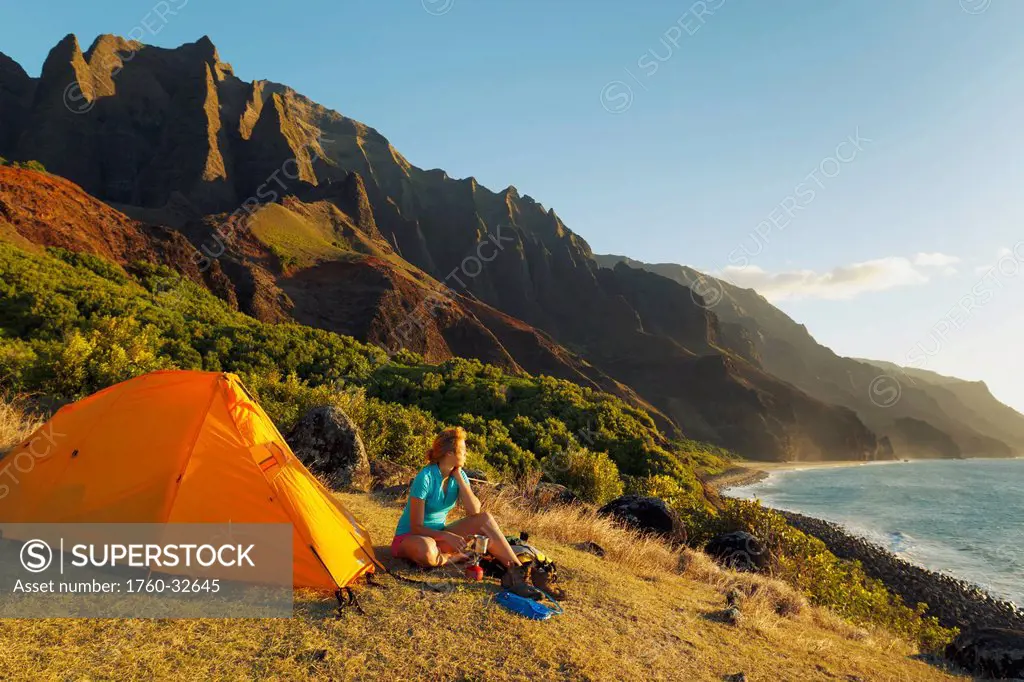 Hawaii, Kauai, Na Pali Coast, View Of The Kalalau Mountains And Ocean, Female Camper Enjoys The Scenery.