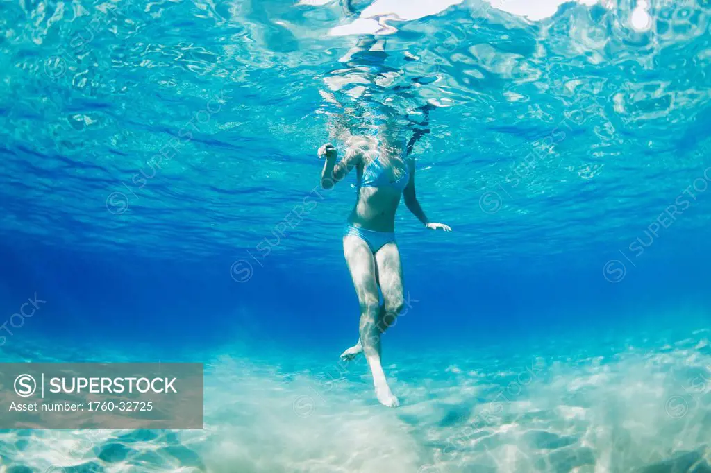 Hawaii, Maui, Makena, Young Woman Swimming Near Ocean Surface, View From Below.