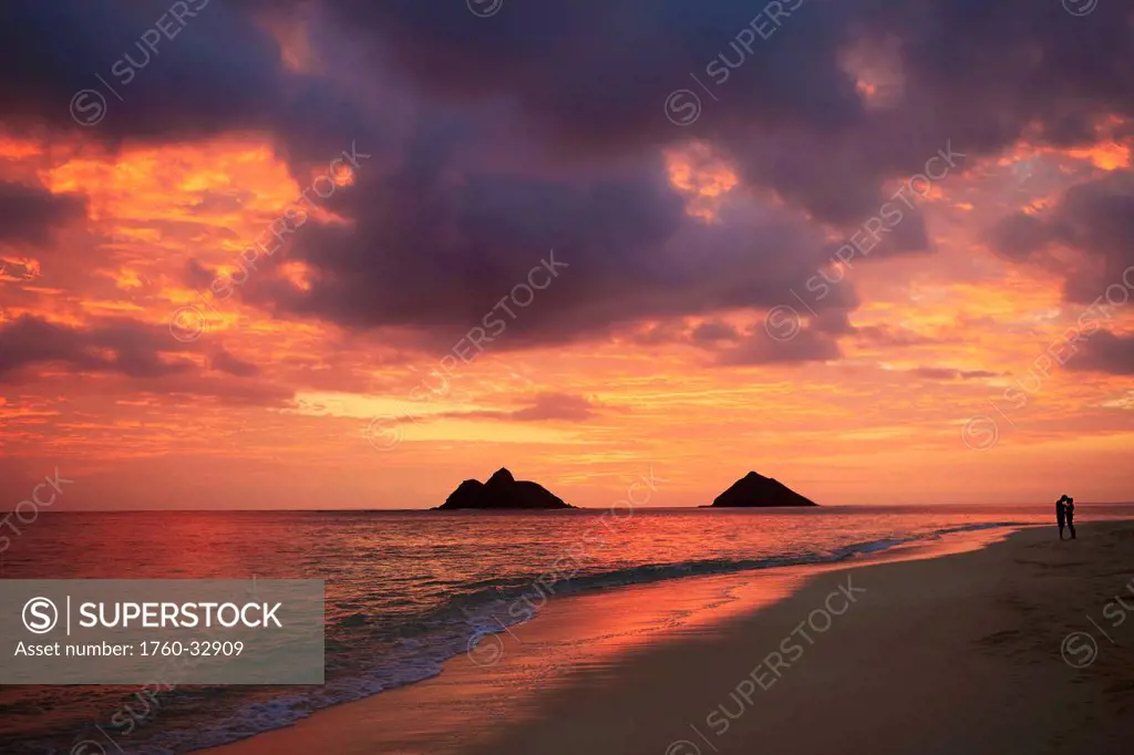 Hawaii, Oahu, Kailua, Lanikai, Vibrant Sunset With A Couple Embracing On Beach.
