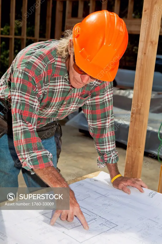 Hawaii, Senior Male Construction Worker Reading Blueprints At A Construction Site.