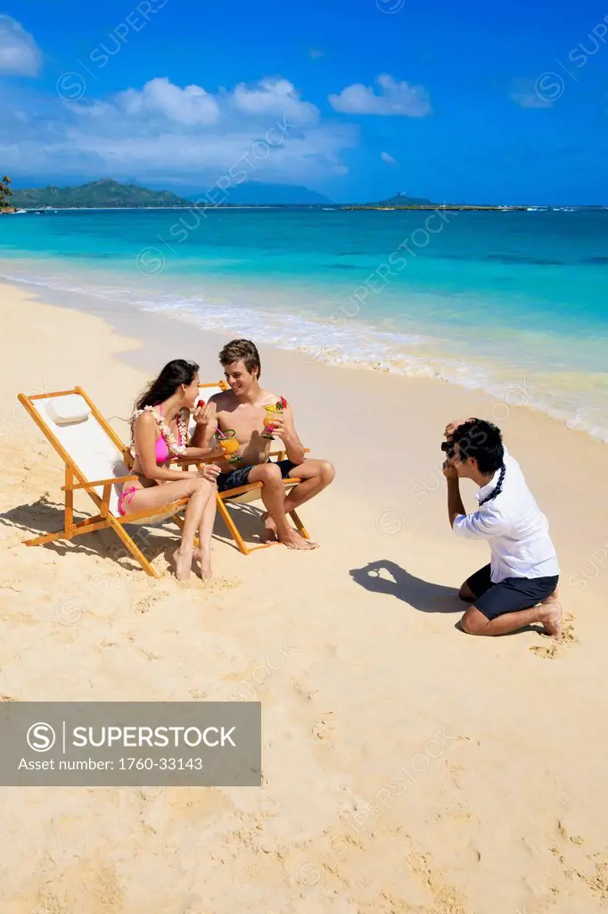 Hawaii, Oahu, Lanikai, A Beachboy Takes A Picture Of A Young Couple On The Beach.