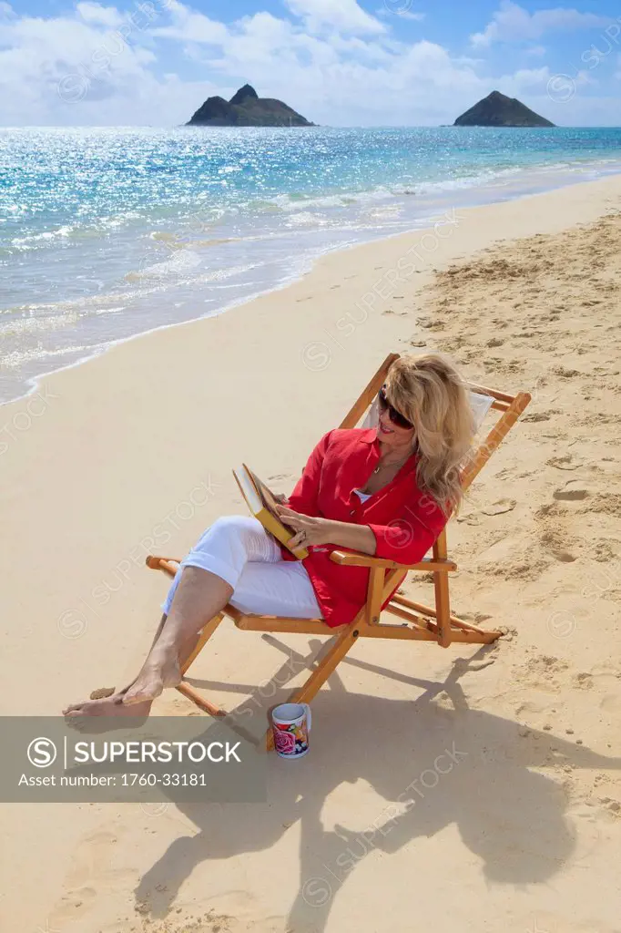 Hawaii, Oahu, Lanikai Beach, Woman Reads Book On White Sandy Beach.