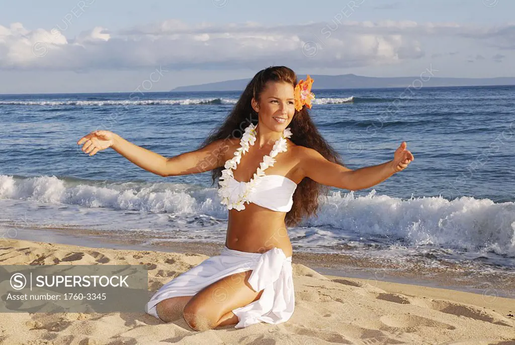 Beautiful Hawaiian girl dancing hula on ocean shoreline