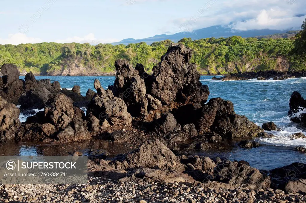 Hawaii, Maui, Keanae, A view of rocky shore in front of lush cliffs.
