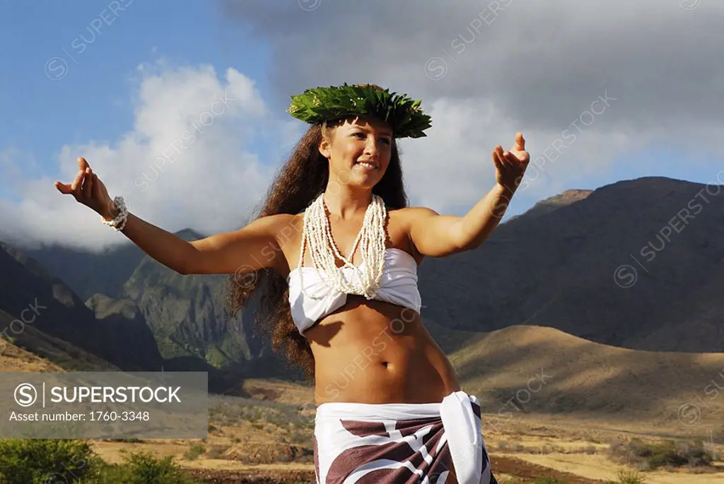 Beautiful Hawaiian girl dancing with mountains in the background