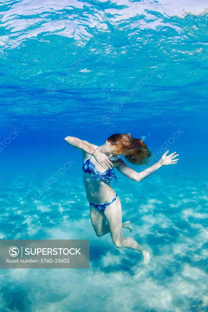 Hawaii, Lanai, Manele Bay, Young woman dancing in shallow water.