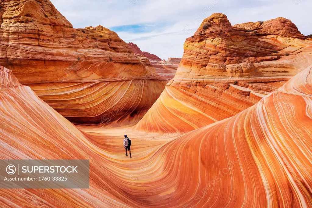 Arizona, Page, North Coyote Buttes, A hiker explores The Wave rock formation.