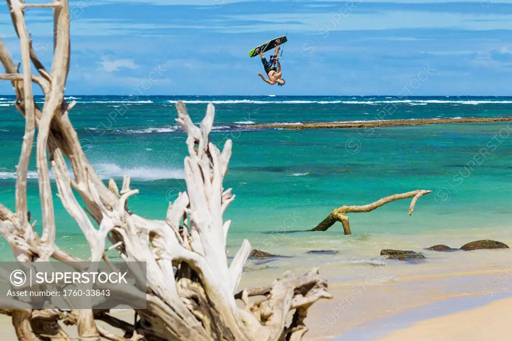 Hawaii, Maui, Professional Kiteboarder Shawn Richman, Driftwood in foreground. EDITORIAL USE ONLY.