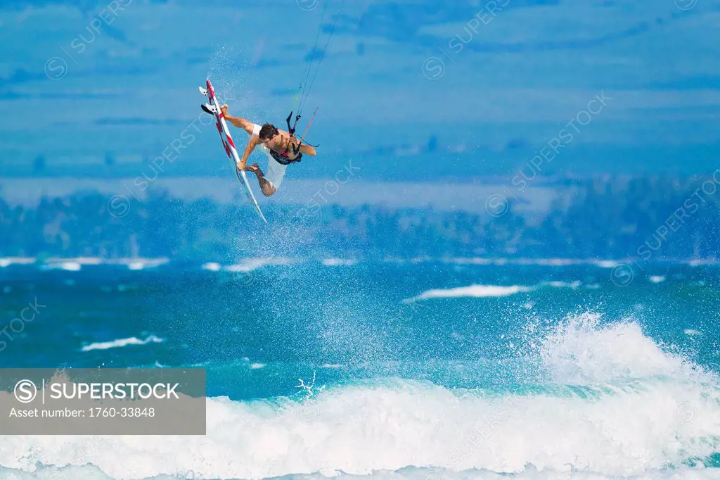 Hawaii, Maui, Professional Kiteboarder Niccolo Porcella catching air off the North Shore, Ocean spray in the foreground. EDITORIAL USE ONLY.