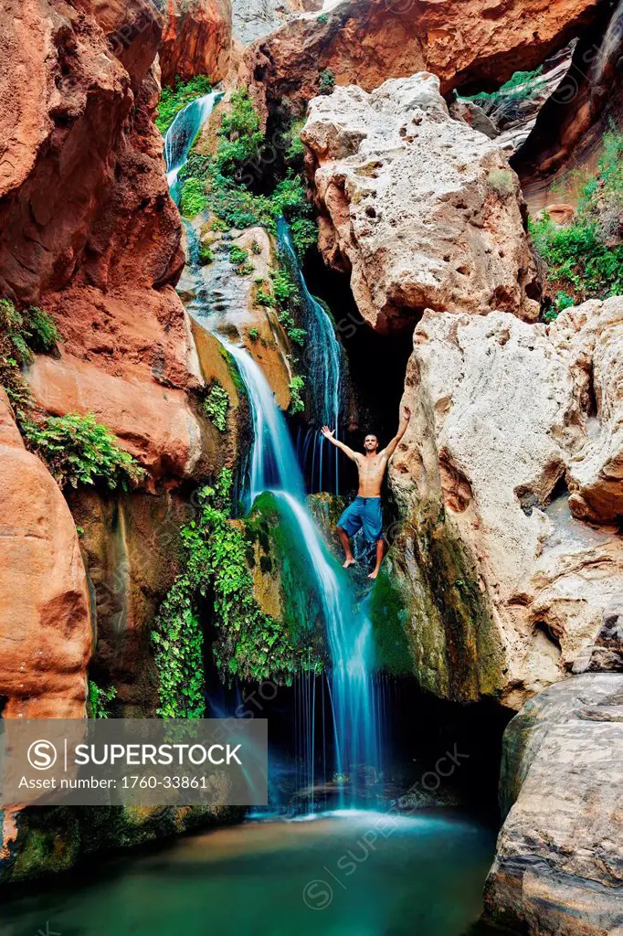 Arizona, Grand Canyon National Park, Young man standing above the waterfall at Elves Chasim.