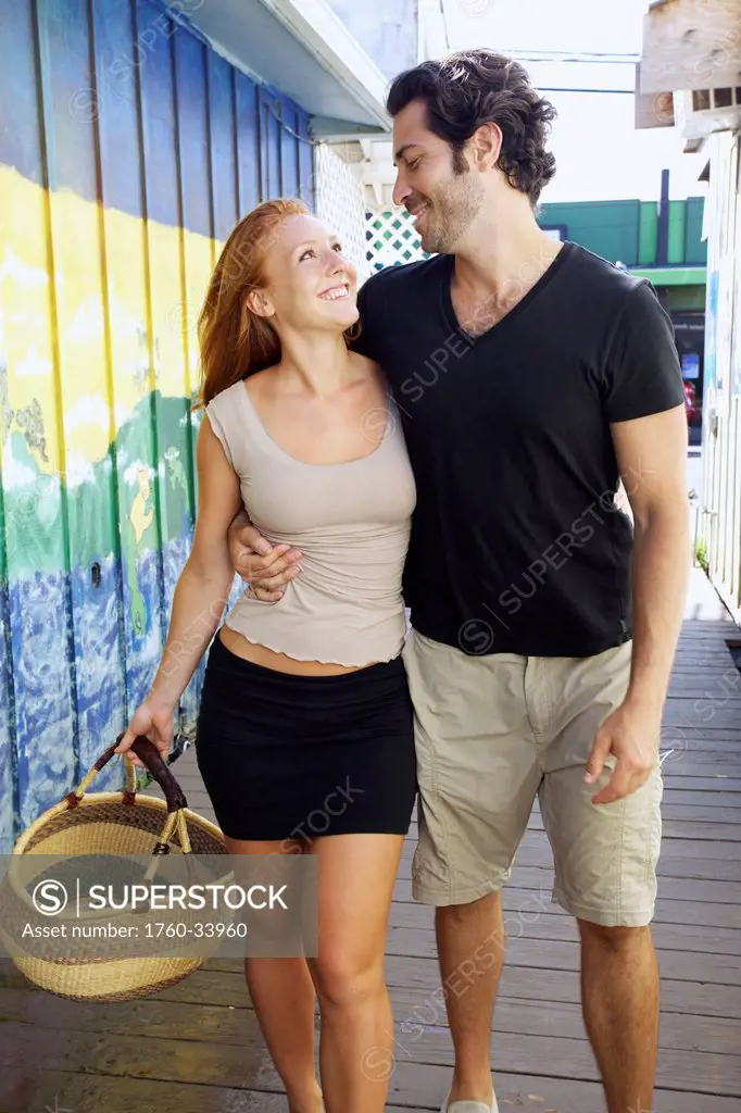 A couple walks together outside retail shops; Kapaa, Kauai, Hawaii, United States of America