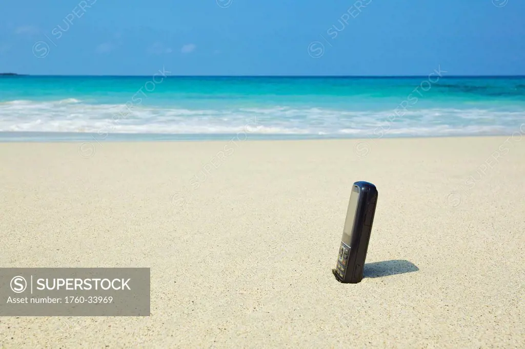 A bottle of sunscreen stuck in the sand on a beach; Wailua, Hawaii, United States of America