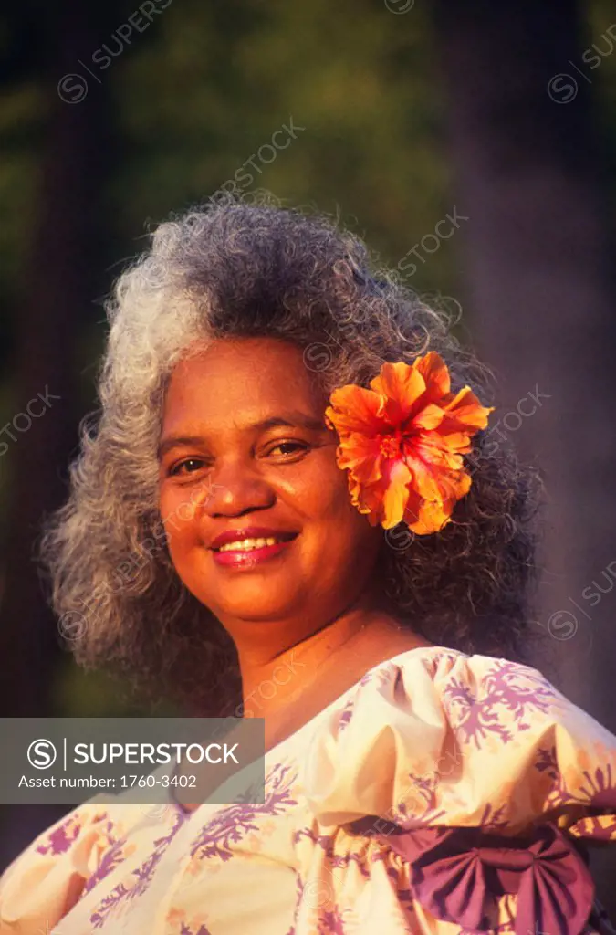 Portrait of pure Hawaiian woman in muumuu, smiling with hibiscus in her hair