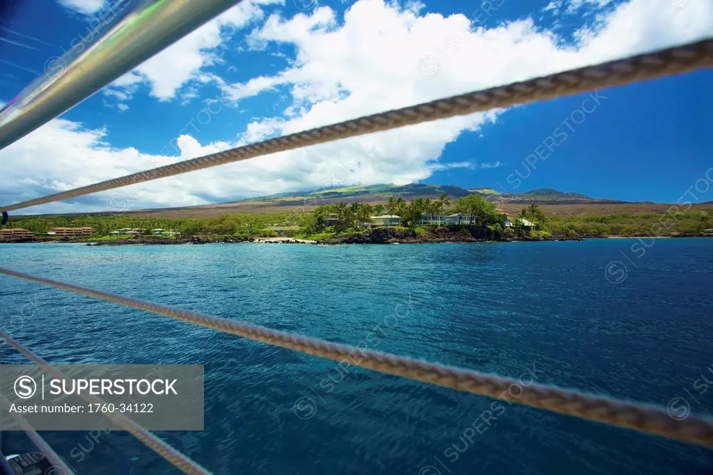 View of the coastline of an hawaiian island through the railing of a boat; Hawaii, United States of America