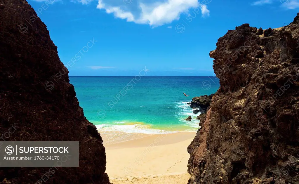 A person jumping off the rugged rocks on the coast of an hawaiian island; Hawaii, United States of America