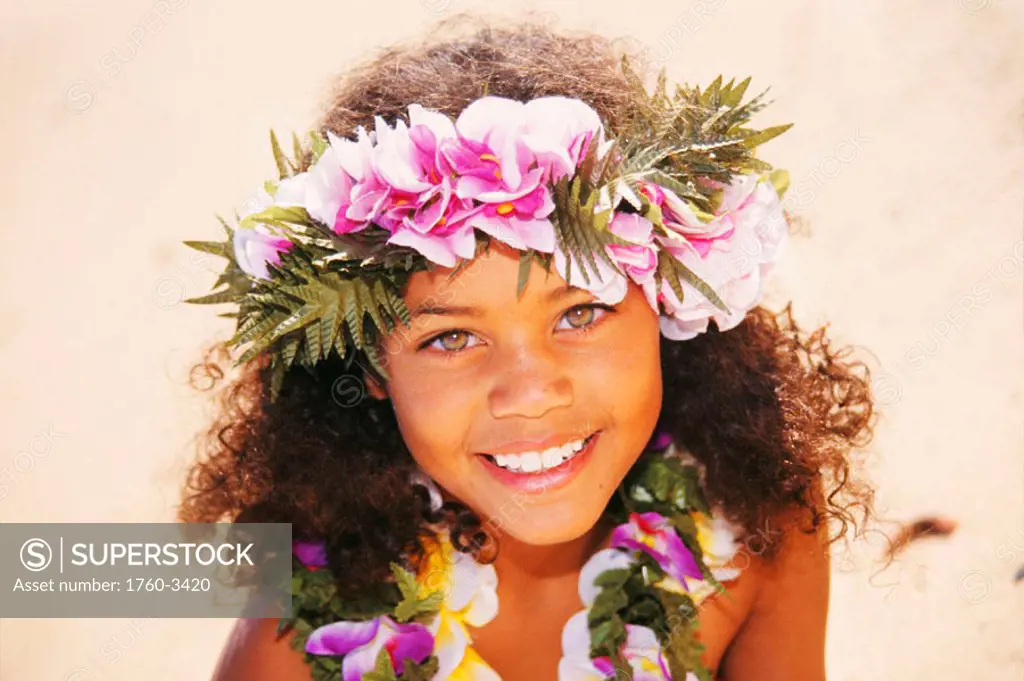 Head shot of young hula girl on beach, smiling, colorful haku and lei, white sand