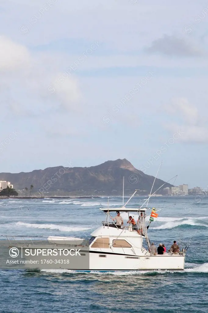 A fishing boat comes back to the Honolulu Yacht Harbor, with Diamond Head in the background; Honolulu, Oahu, Hawaii, United States of America