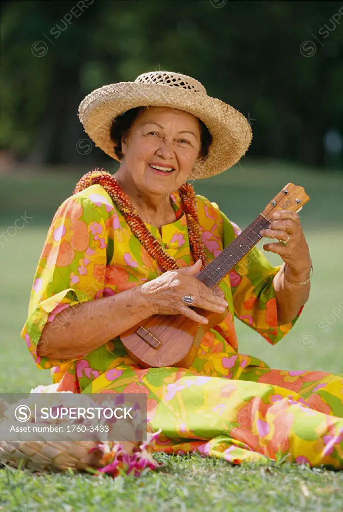 Senior woman sitting in park playing ukulele, closeup front view, smiling C1503