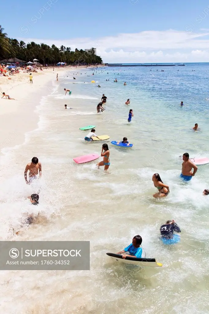 Locals and tourists swim and play in ocean at Waikiki Beach; Waikiki, Oahu, Hawaii, United States of America