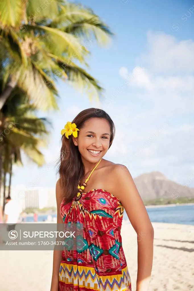 Portrait of a woman on a beach with a tropical flower in her hair; Waikiki, Oahu, Hawaii, United States of America