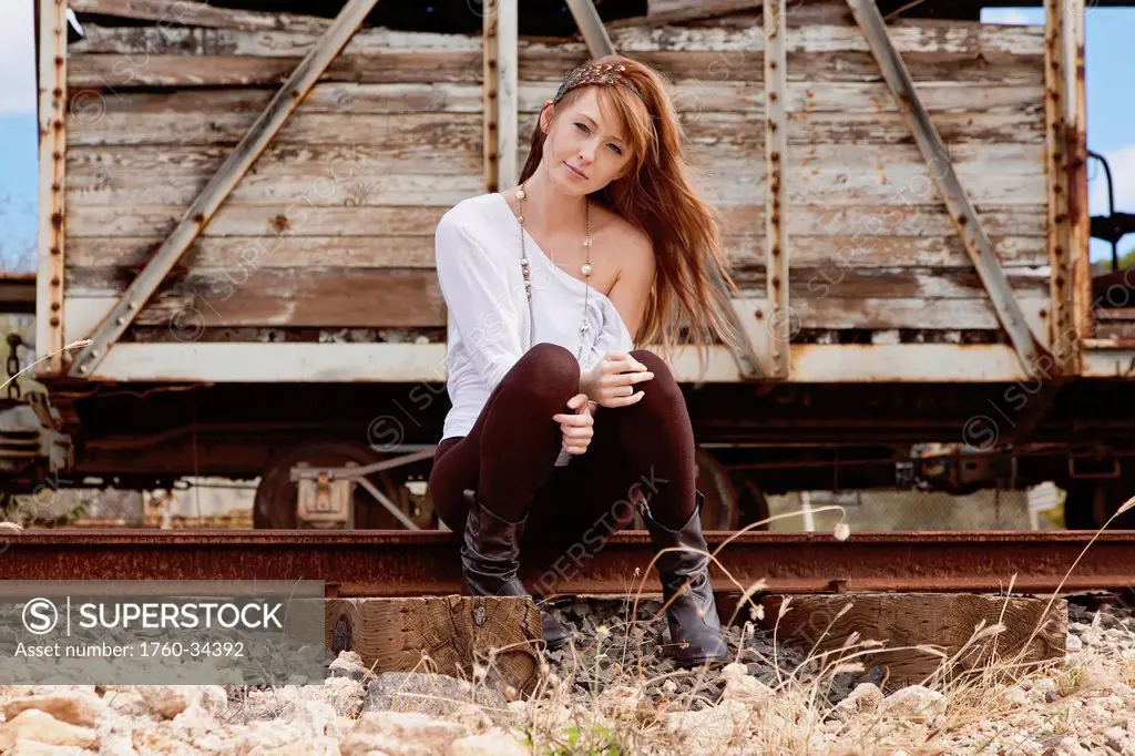 A young woman poses on train tracks; Honolulu, Oahu, Hawaii, United States of America
