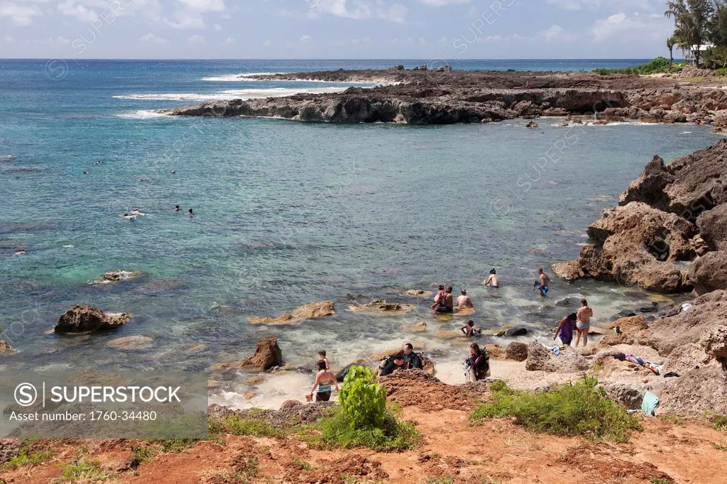 People swimming around the rocks along the rugged coast; Honolulu, Oahu, Hawaii, United States of America