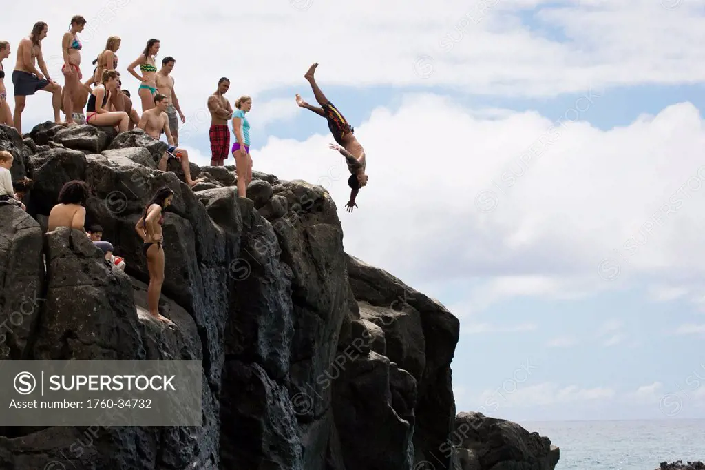 People enjoy a 30 foot high jump at da big rock in Waimea Bay; North Shore, Oahu, Hawaii, United States of America