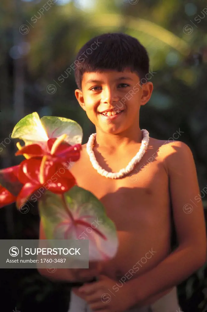 Close-up smiling Hawaiian boy with puka necklace holding Red Anthurium