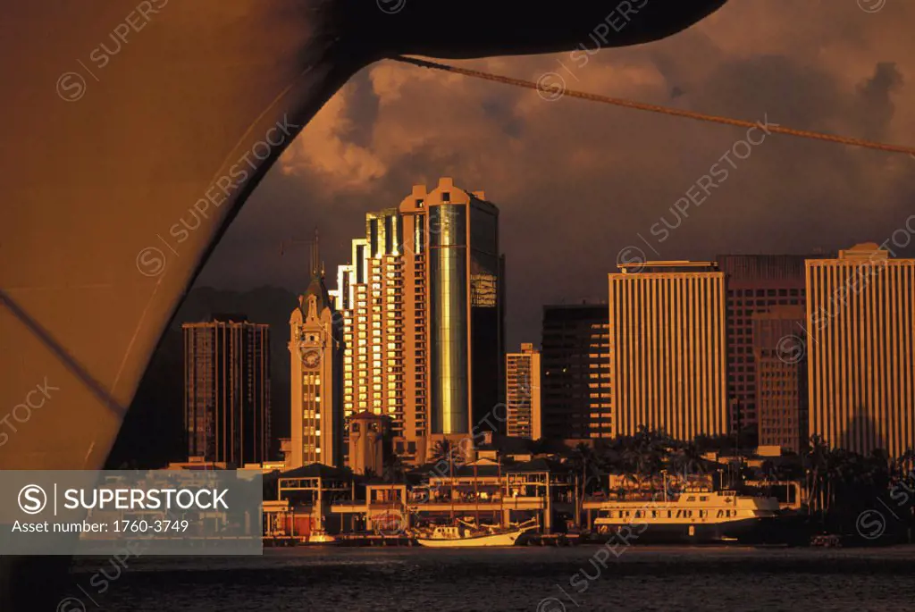 Hawaii, Oahu, Honolulu, Aloha Tower, Honolulu harbor, and downtown cast in a golden hue framed with ship