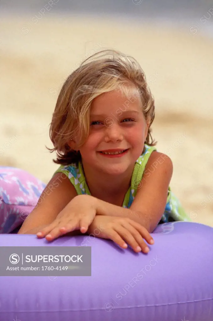 Close-up of girl on beach, leaning over purple inner tube
