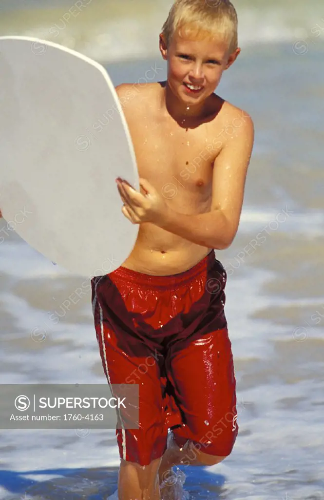 Hawaii, Maui, young Caucasian boy launching skimboard at Baldwin beach