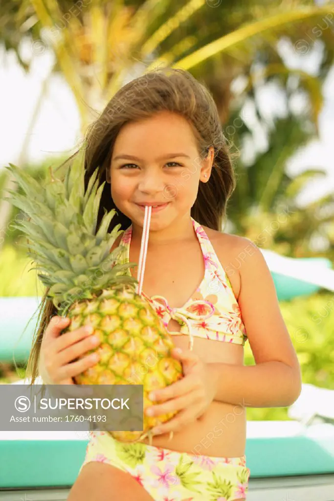 Little girl drinking from pineapple.