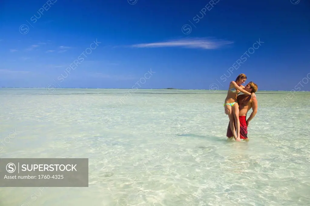 Hawaii, Oahu, Kaneohe, couple stand in crystal clear water at the sandbar or ´dissapearing island´