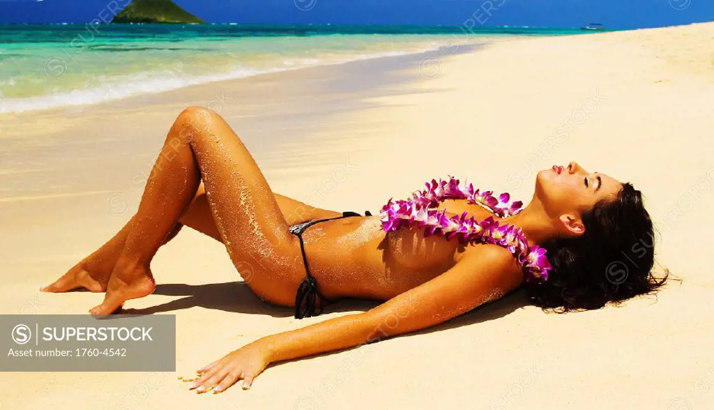 Hawaii, Oahu, Lanikai, Sexy young woman laying on the beach wearing orchid lei