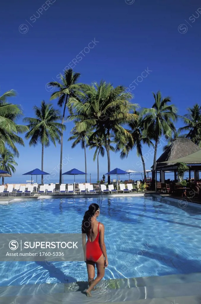 Fiji, Coral Coast, Shangri-La resort, Woman wading in pool, palms and blue sky.