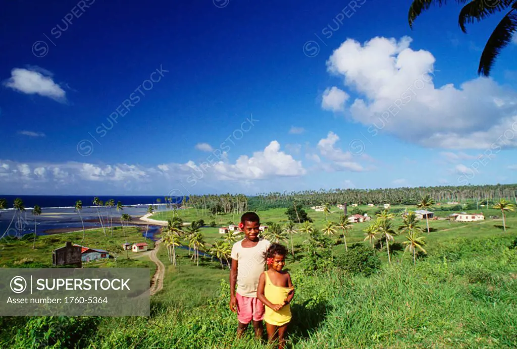 Fiji, Salialevu Town, Children stand amongst a beautiful tropical landscape