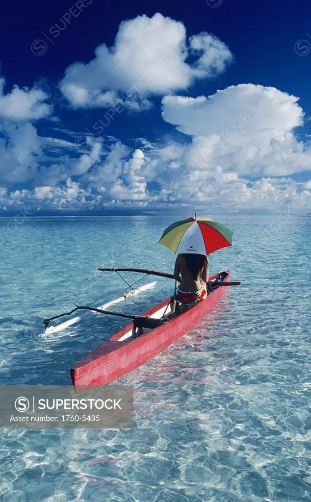 French Polynesia, Tetiaroa, Local woman in outrigger canoe with umbrella, View from behind