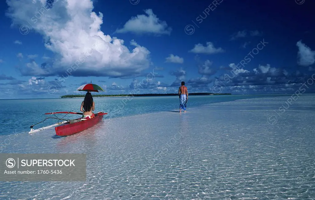 French Polynesia, Sandbar at Tetiaroa, Local woman in outrigger canoe with umbrella, Man walking in distance, View from behind