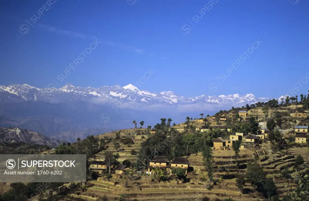 Nepal, village near Nagarkot, distant overview of terraces, Himalayan mountains in background.
