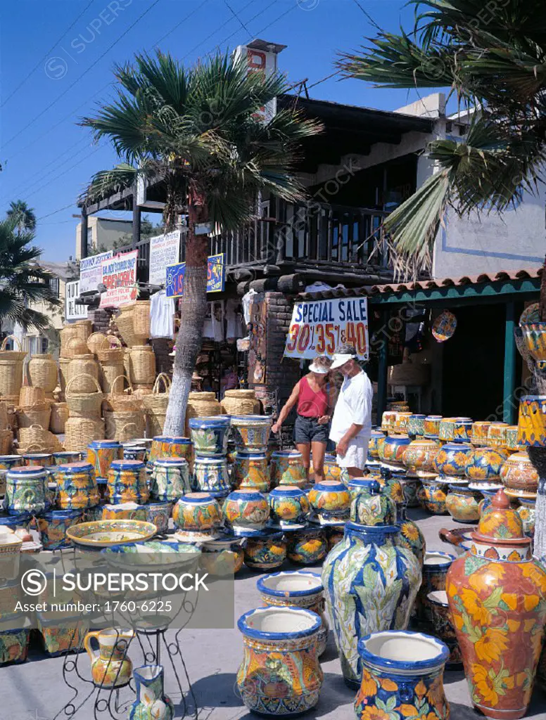 Mexico, Tijuana, couple wanders thru marketplace stand, ceramic pots C1764