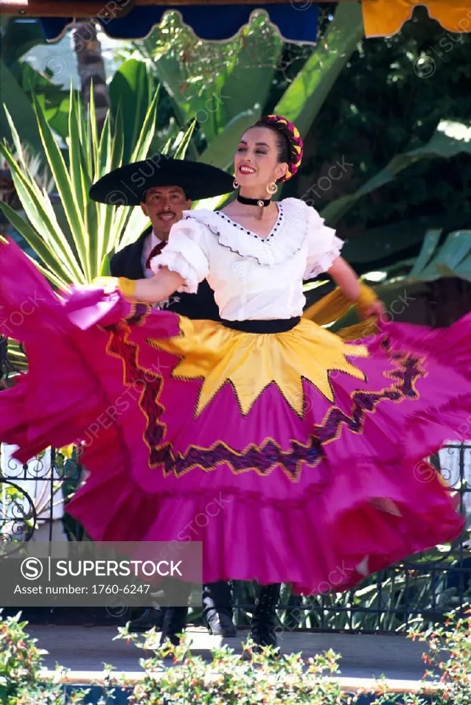 Mexico, couple in bright dance costumes, smiling, woman swings skirt C1762