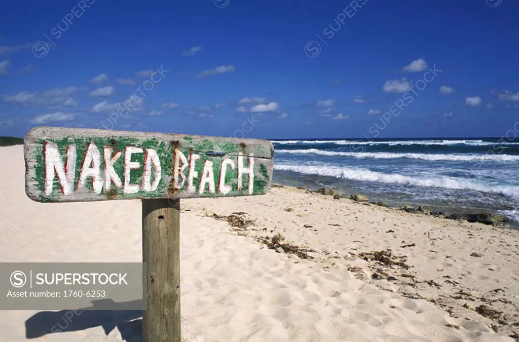 Mexico, Yucatan Peninsula, Cozumel, ´Naked Beach´ sign in sand, ocean and blue sky in background.