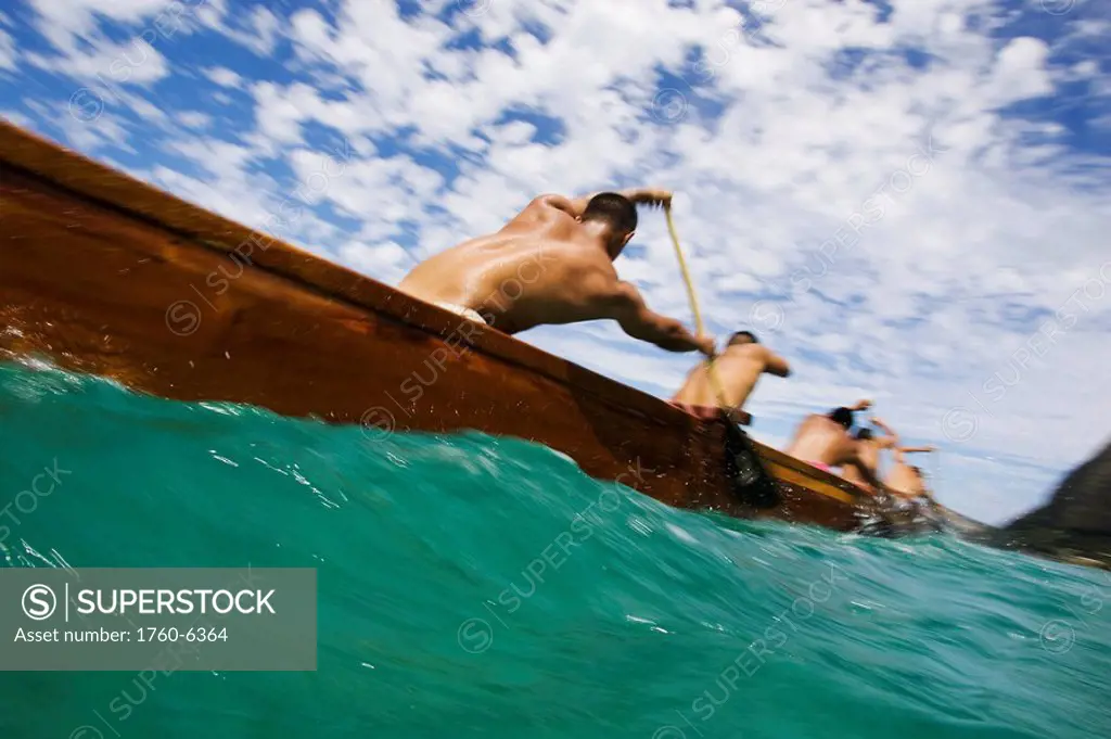 Hawaii, Oahu, Waimanalo, Male outrigger canoe team paddling hard through blue-green ocean 