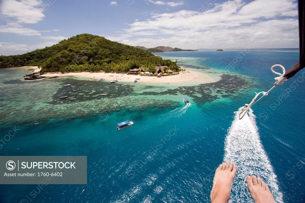Fiji, Mamanucas, Castaway Island, reef and islands from the aerial viewpoint of a parasailer, feet hanging in frame 