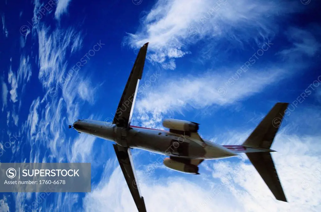 Hawaii, view from below of airplane taking off into bright blue sky 